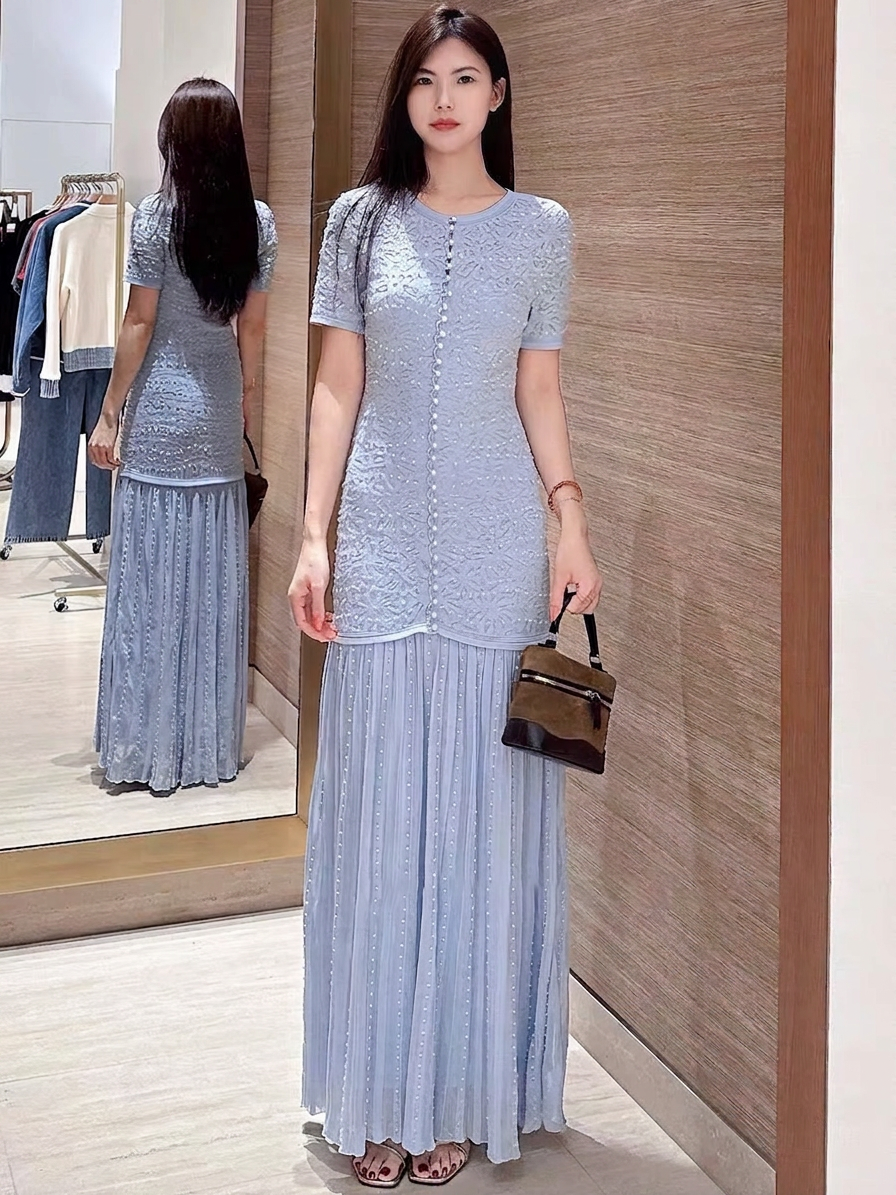 Elegant light blue lace maxi dress Woman wearing a light blue lace maxi dress standing indoors holding a small handbag